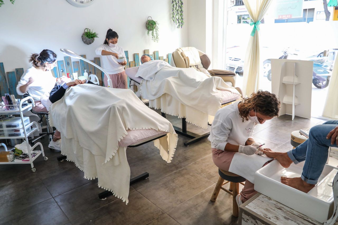 Peaceful spa scene with professionals giving facial and pedicure treatments in a well-lit salon.